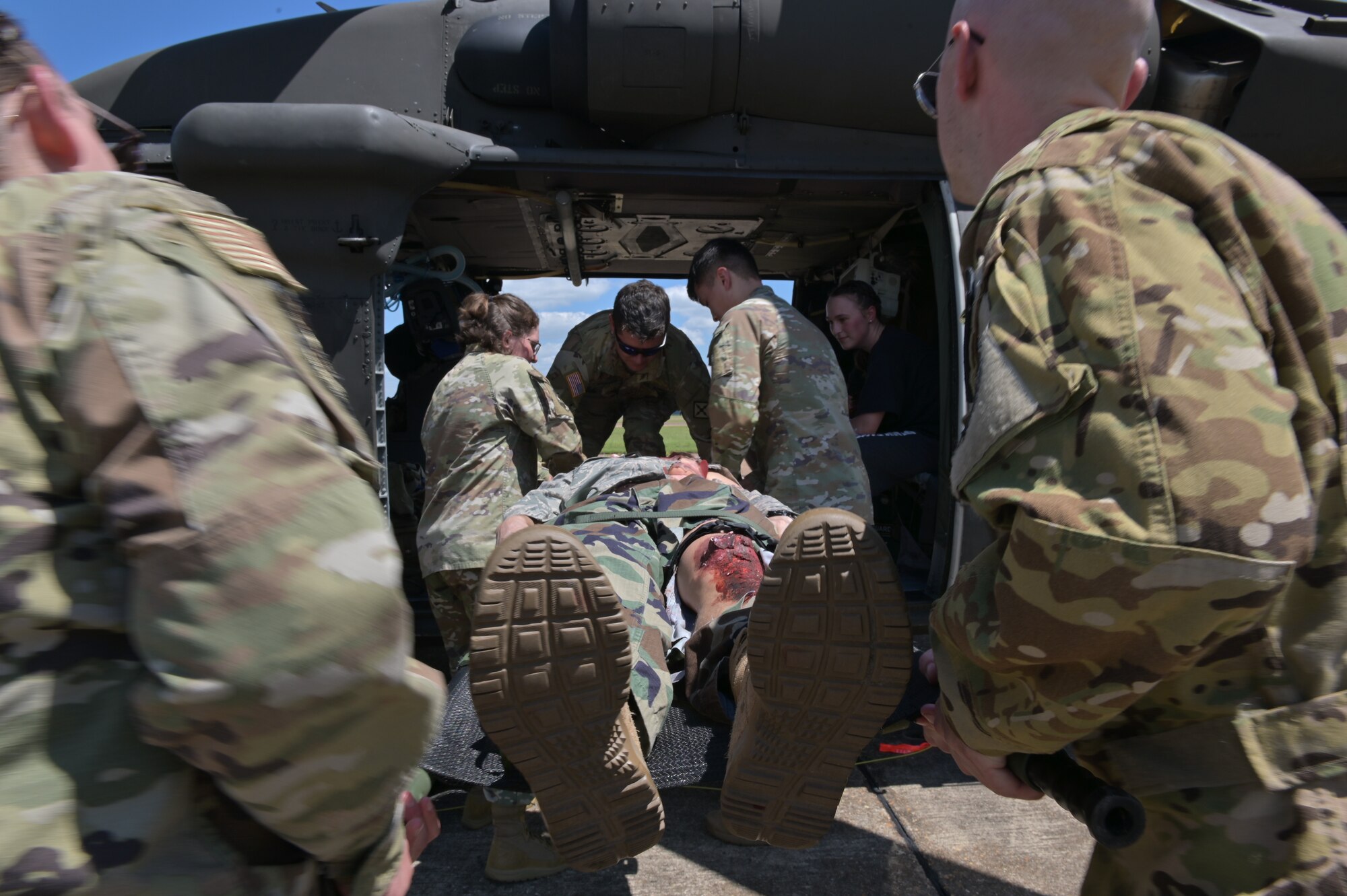 Service members load a simulated patient onto a Blackhawk helicopter.