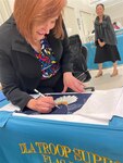 woman signs unfinished flag with eagle embroidery