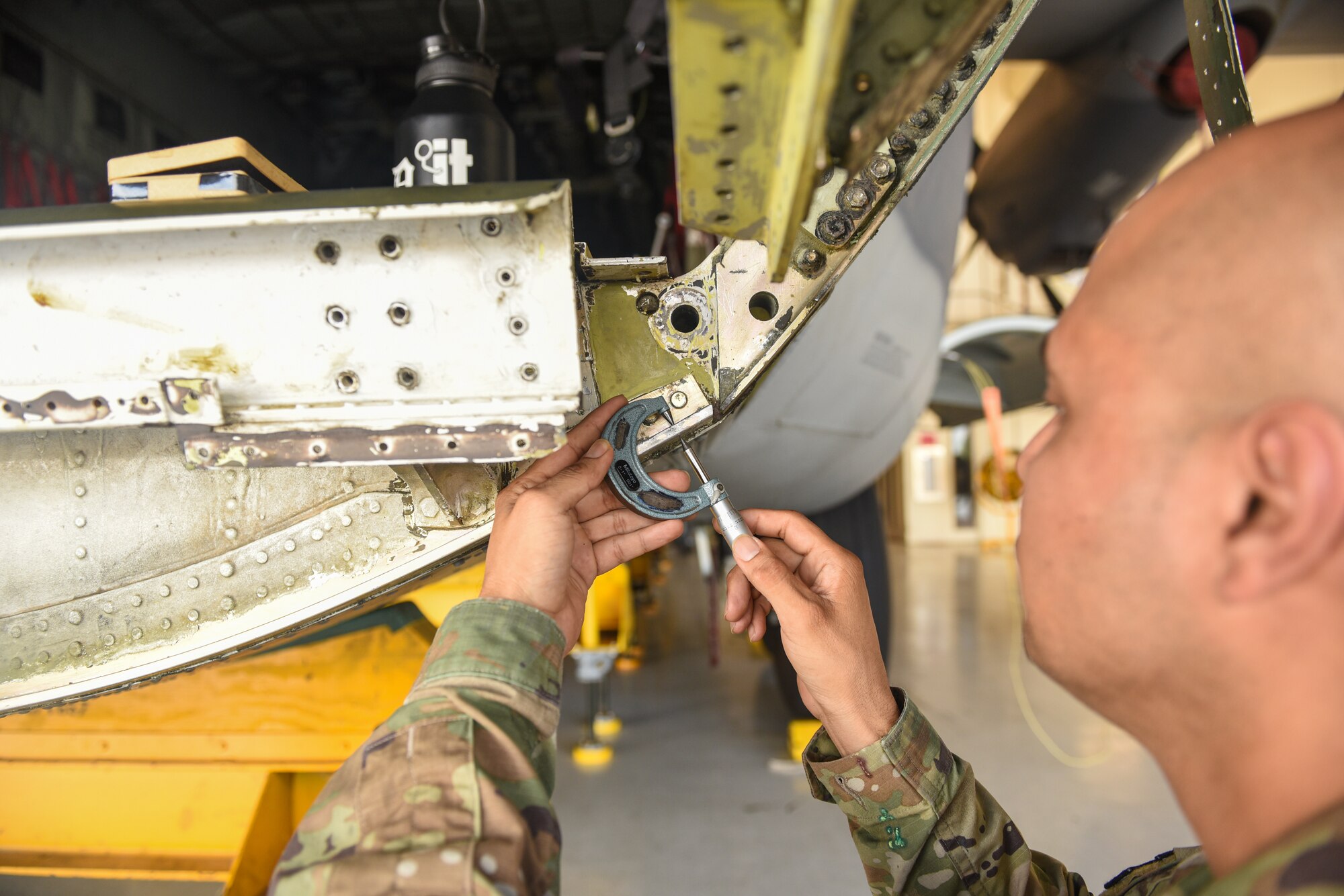 U.S. Air Force Tech. Sgt Kenneth Martinez, 23rd Maintenance Squadron aircraft structural maintenance section chief, uses a micrometer to measure the metal thickness on the bulkhead area of an HC-130J Combat King II during a corrosion repair at Moody Air Force Base, Georgia, Aug. 10, 2023. This measurement identifies the degree of corrosion to the metal of the aircraft. (U.S. Air Force photo by Senior Airman Courtney Sebastianelli)