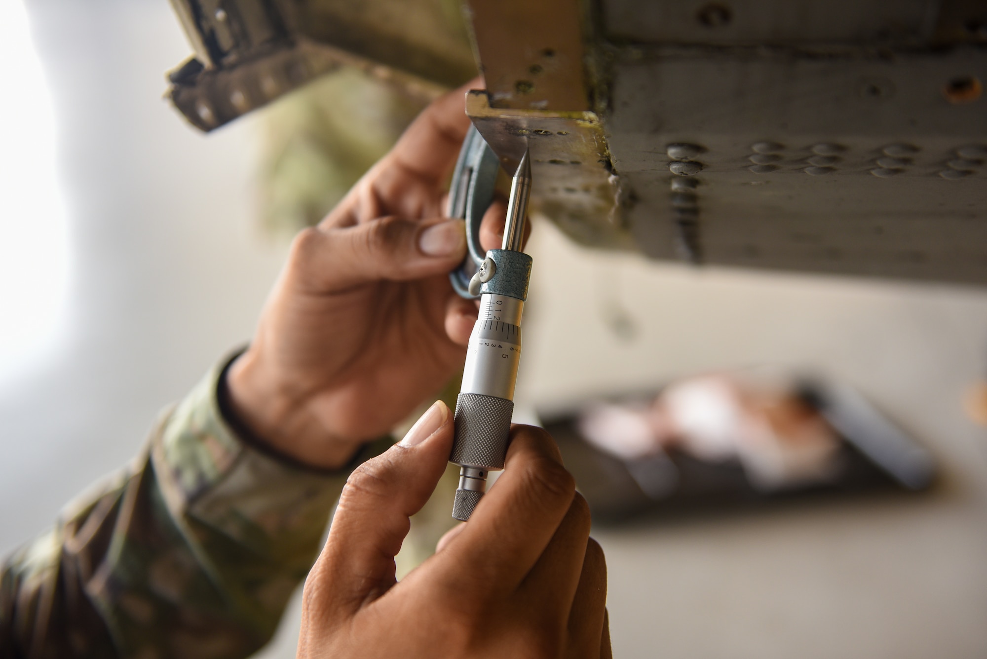 U.S. Air Force Tech. Sgt Kenneth Martinez, 23rd Maintenance Squadron aircraft structural maintenance section chief, uses a micrometer to measure the metal thickness on the bulkhead area of an HC-130J Combat King II during a corrosion repair at Moody Air Force Base, Georgia, Aug. 10, 2023. Standard types of micrometers can be used for the fine measurement of items under one inch in length, depth, and thickness. (U.S. Air Force photo by Senior Airman Courtney Sebastianelli)