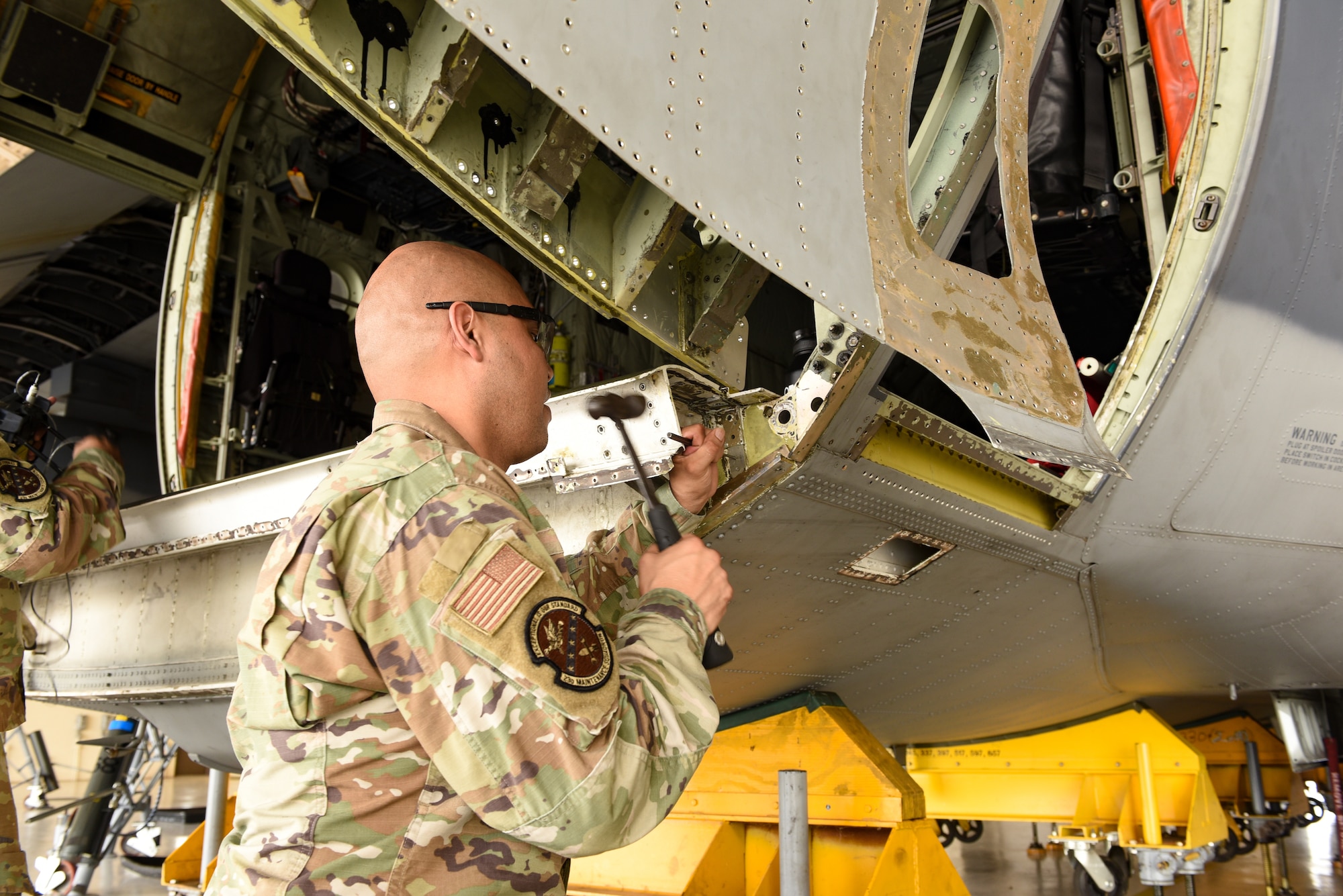 U.S. Air Force Tech. Sgt Kenneth Martinez, 23rd Maintenance Squadron aircraft structural maintenance section chief, hammers the bulkhead area of an HC-130J Combat King II during a corrosion repair at Moody Air Force Base, Georgia, Aug. 10, 2023. Corrosion was found during a routine inspection of the aircraft’s bulkhead area. (U.S. Air Force photo by Senior Airman Courtney Sebastianelli)
