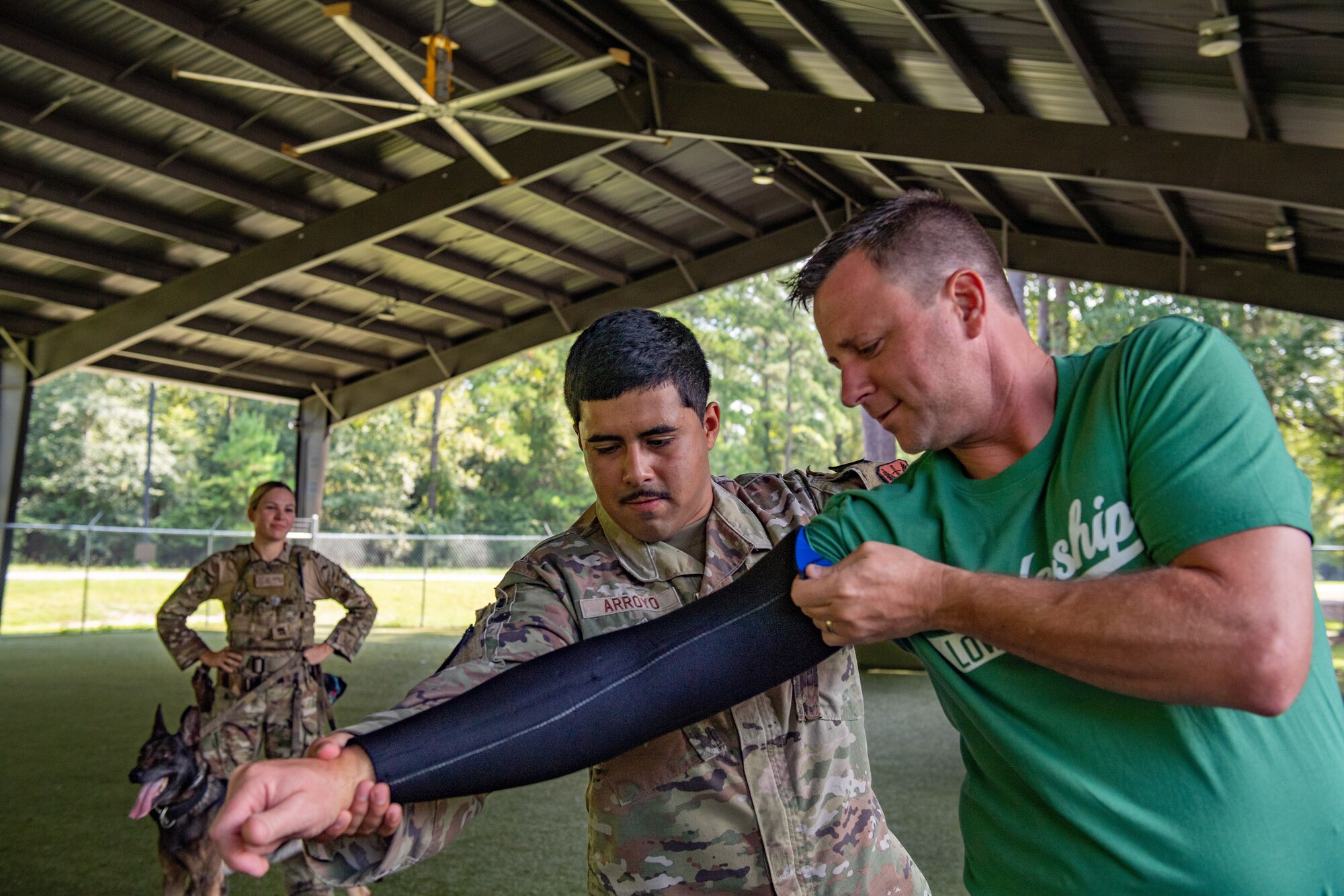 U.S. Air Force Staff Sgt. Marco Arroyo, 23rd Security Forces military working dog trainer, and a Leadership Lowndes class participant work together to don a protective sleeve during a Defense Day tour at Moody Air Force Base, Georgia, Aug, 17, 2023. The Leadership Lowndes class participants had the opportunity to interact with Airmen, military working dogs, military first responders and had the opportunity to explore an A-10C Thunderbolt II. (U.S. Air Force photo by Senior Airman Courtney Sebastianelli)