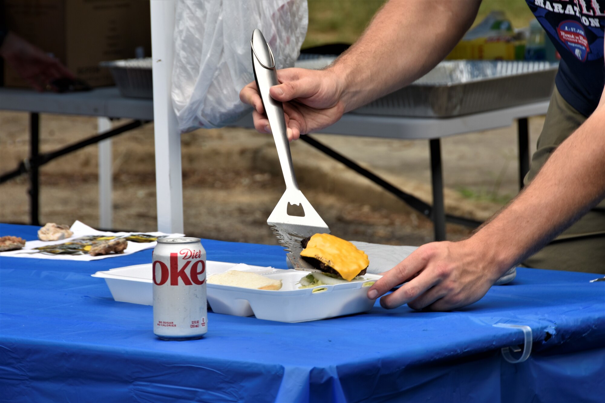 Patrons prepare burgers hot off the grill with all the fixings for lunch thanks to the members of the Arnold Air Force Base Company Grade Officers’ Council. The CGOC hosted the Burger Burn and Car Show July 27, 2023, at Arnold AFB, Tenn. (U.S. Air Force photo by Brooke Brumley)