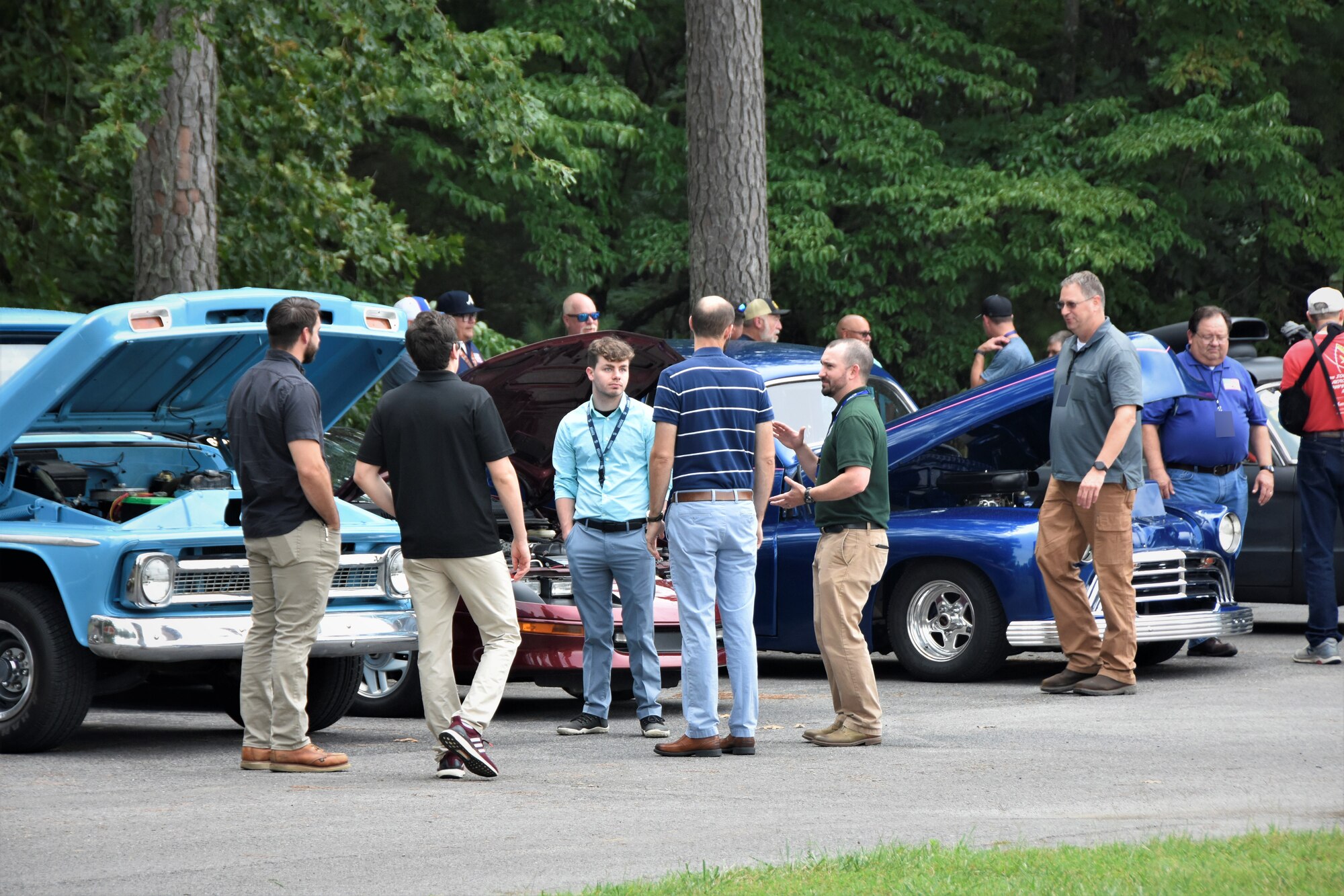 Personnel at Arnold Air Force Base, Tenn., take a lunch break to view the cars on July 27, 2023, during the Burger Burn and Car Show hosted by the Arnold AFB Company Grade Officers’ Council. (U.S. Air Force photo by Brooke Brumley) (This image was altered by obscuring badges for security purposes.)