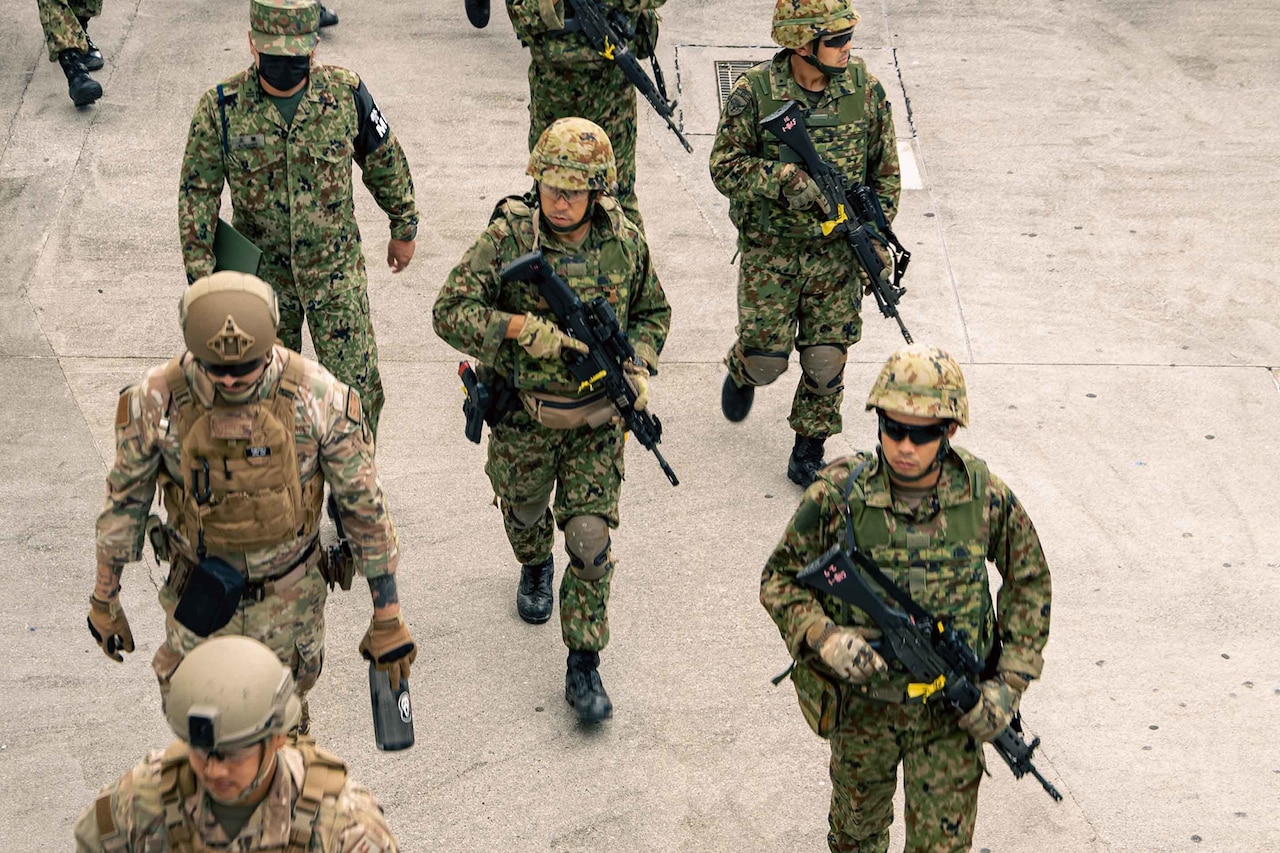 People in uniform patrol a sidewalk while simulating a bilateral search.