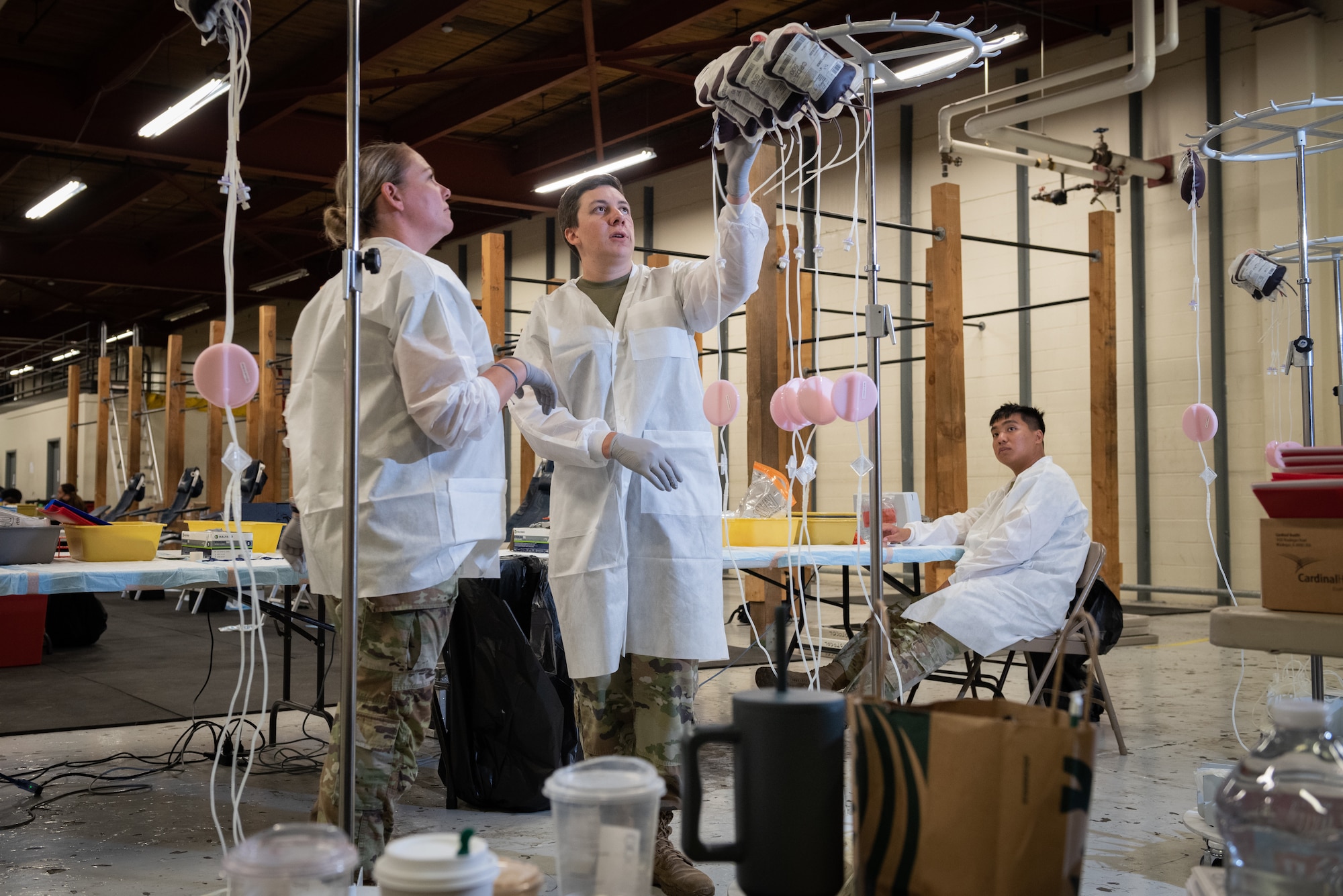 U.S. Army Staff Sgt. Emery Collier, Sgt. Aubree Davis, and Spc. Kyle Xu, inspect bags of donated blood in the Geronimo Gym at Joint Base Elmendorf-Richardson, Alaska,
