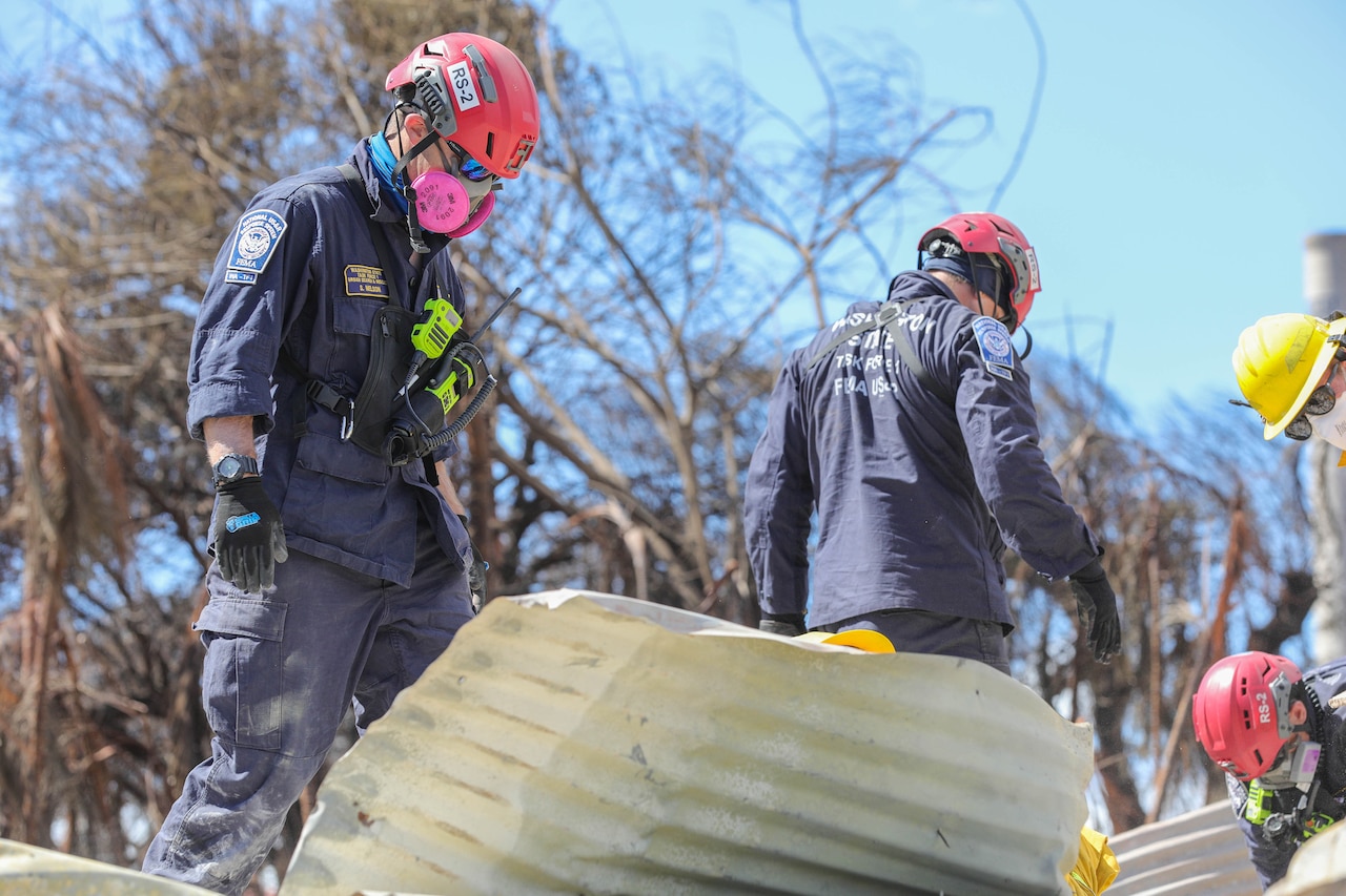 Workers in work suits comb through debris.