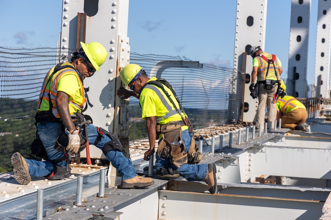 Photo shows contractors working on a bridge