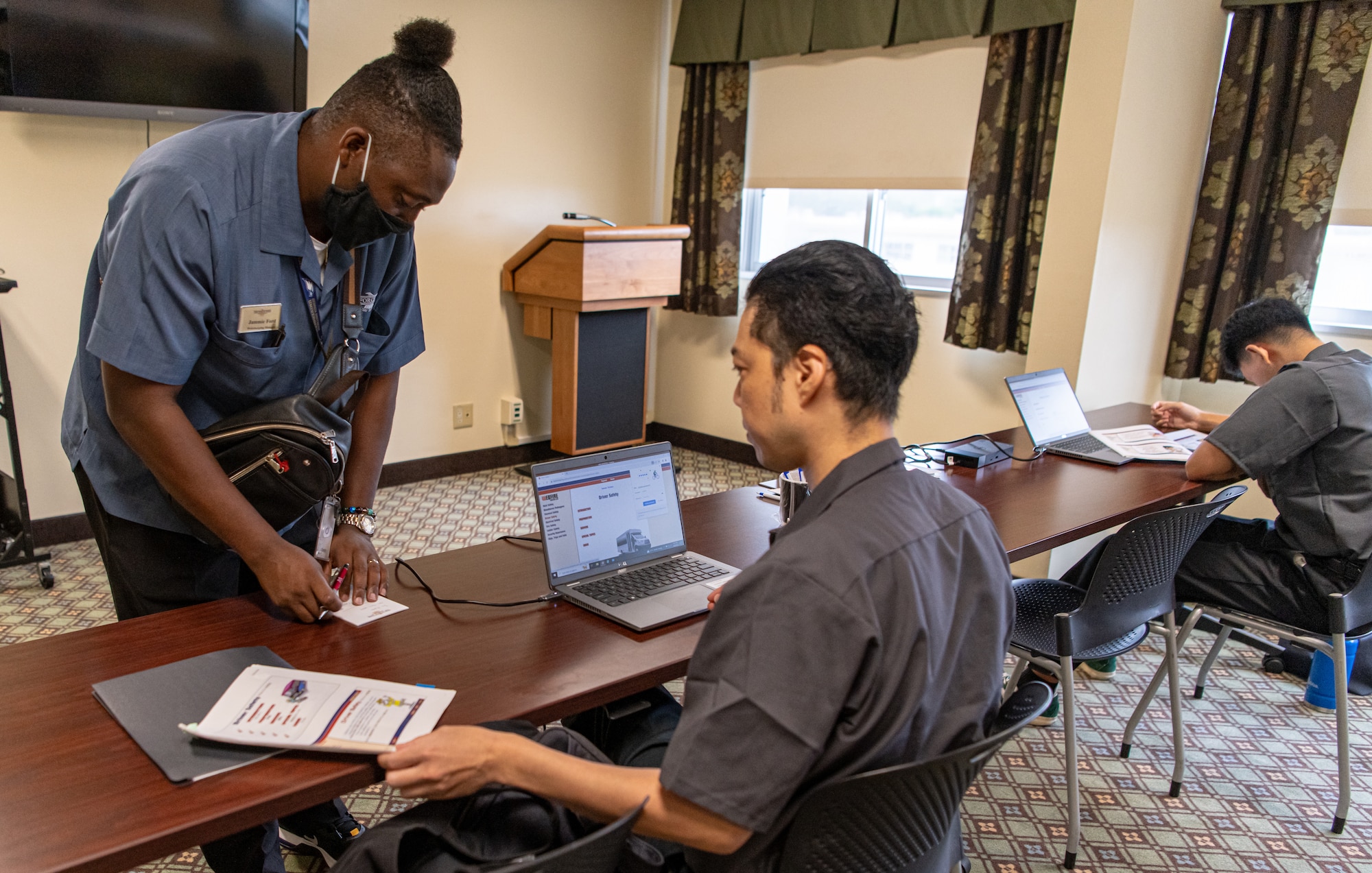 Two men study safety training, one man writes down information.