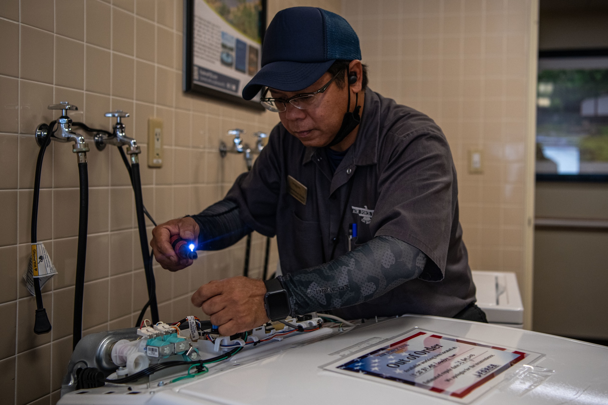 A Shogun Inn maintenance worker repairs a washing machine.