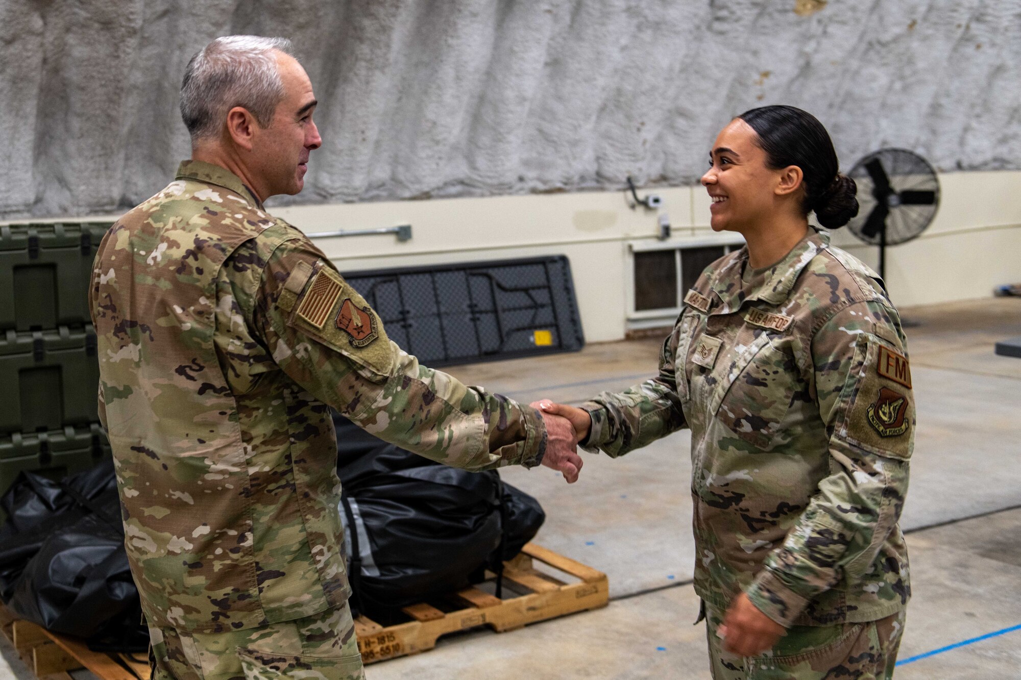 U.S. Air Force Chief Master Sgt. Kristopher Berg, 11th Air Force command chief, coins U.S. Air Force Staff Sgt. Pamela Martinez, Kadena Innovations Lab noncommissioned officer in charge.