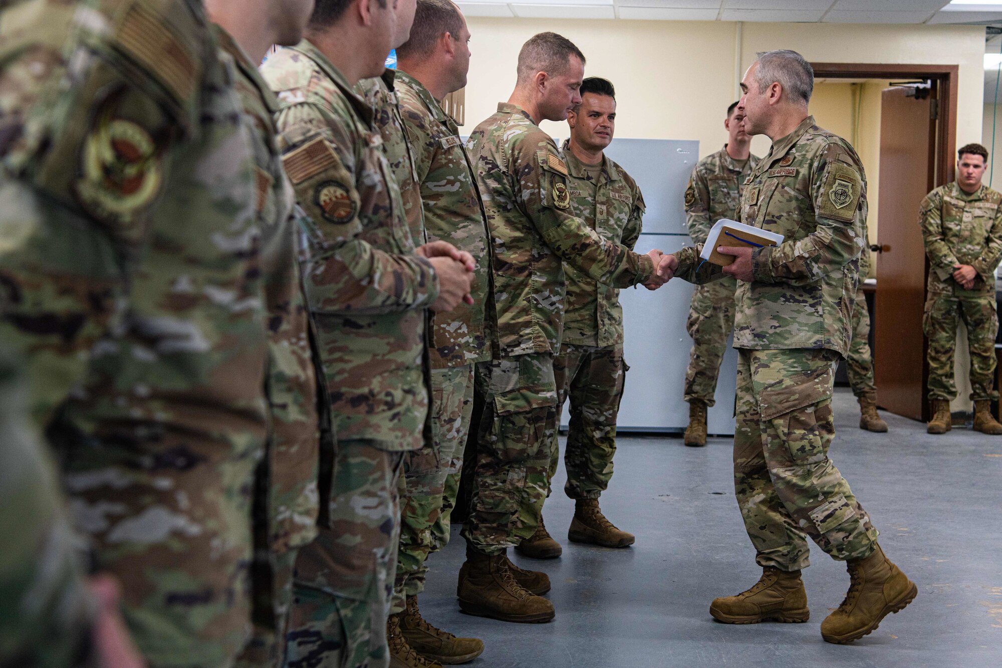 U.S. Air Force Chief Master Sgt. Kristopher Berg, right, 11th Air Force command chief, shakes hands with U.S. Air Force Tech. Sgt. Andrew Okenfuss, 355th Fighter Generation Squadron F-35 technician expeditor.