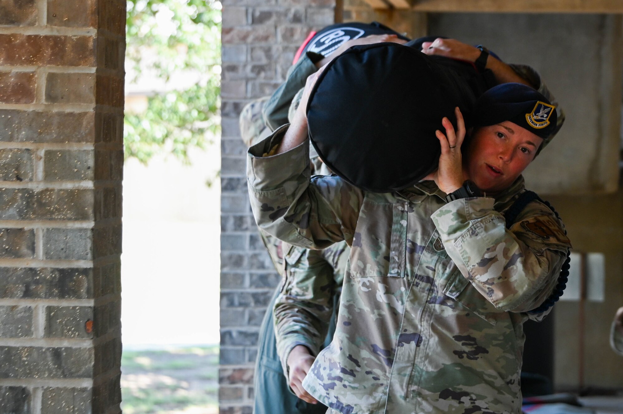 U.S. Air Force Tech. Sgt. Lindsay May 97th Training Squadron military training leader, carries a sandbag with the help of her Airmen at Altus Air Force Base, Oklahoma, Aug. 16, 2023. “Throughout my career I’ve been challenged with uncomfortable situations that tested my abilities. During those challenges I would smile, embrace the situation and work harder to grow my comfort levels.” (U.S. Air Force photo by Airman 1st Class Miyah Gray)