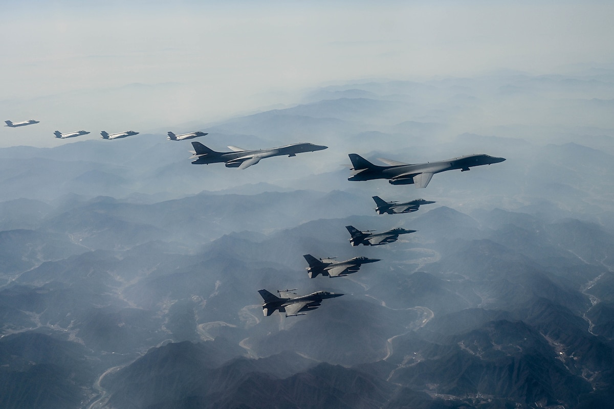Ten planes fly in formation above the clouds.