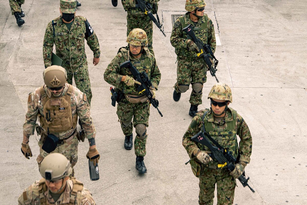 People in uniform patrol a sidewalk while simulating a bilateral search.