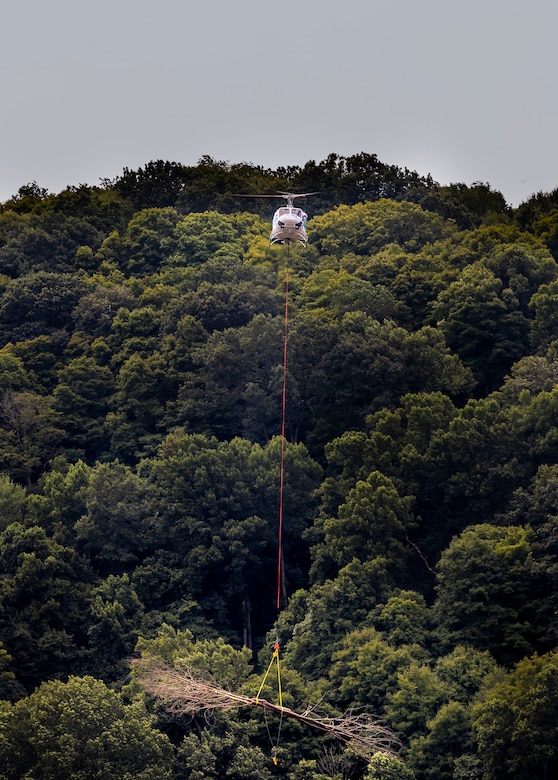 A helicopter lifting trees and concrete blocks to place them in a water basin on the Ohio River.