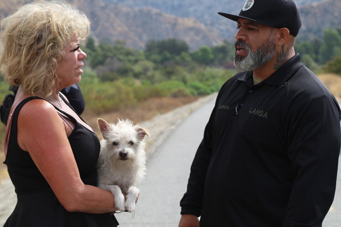 A representative with the Los Angeles Homeless Services Authority speaks with a homeless individual Aug. 19 near the riverbeds of the Santa Fe Dam in Azusa, California. Multiple law enforcement agencies, including the LA County Sheriff’s Department’s Homeless Outreach Service’s Team, Azusa and Irwindale police departments; the U.S. Army Corps of Engineers Los Angeles District’s Operations Division; and the Los Angeles Homeless Services Authority collaborated on efforts to evacuate homeless individuals near the dam to safety prior to the impending tropical storm Hurricane Hilary.