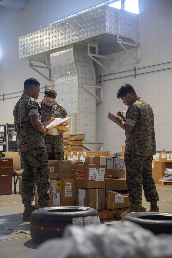 U.S. Marine Corps Lance Cpl. Zachariah Kern, center, a freight transportation clerk with the Marine Corps Air Station Iwakuni Distribution Management Office, Cpl. Trey Brown and PFC Julian Saldana, both aviation supply specialist with Marine Aviation Logistic Squadron 12, Marine Aircraft Group 12, reviews delivery receipts while delivering cargo to Marine Aviation Logistics Squadron 12, Marine Aircraft Group 12, at MCAS Iwakuni, Japan, June 15, 2023. The Distribution Management Office supports tenant commands at the air station by shipping and transporting all mission- essential equipment and supplies. (U.S. Marine Corps Photo by Cpl. Calah Thompson)