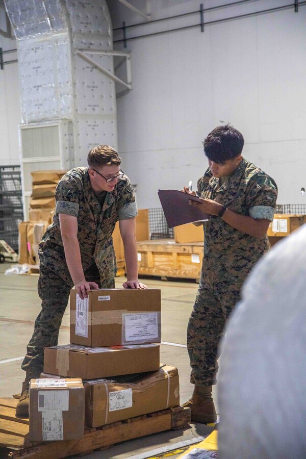 U.S. Marine Corps Lance Cpl. Zachariah Kern, left, a freight transportation clerk with the Marine Corps Air Station Iwakuni Distribution Management Office and PFC Julian Saldana an aviation supply specialist with Marine Aviation Logistic Squadron 12, Marine Aircraft Group 12, checks the label of cargo transported to Marine Aviation Logistic Squadron12 at MCAS Iwakuni, Japan, June 15, 2023. The Distribution Management Office supports tenant commands aboard the air station by shipping and transporting all mission- essential equipment and supplies. (U.S. Marine Corps Photo by Cpl. Calah Thompson)