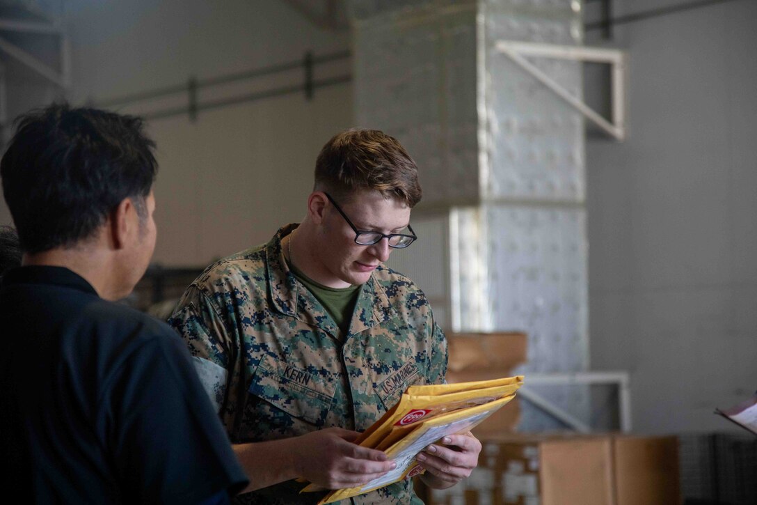 U.S. Marine Corps Lance Cpl. Zachariah Kern, right, a freight transportation clerk with the Marine Corps Air Station Iwakuni Distribution Management Office, oversees cargo distribution documents at MCAS Iwakuni, Japan, June 15, 2023. Transportation specialists coordinate, monitor, and control the movement of equipment and cargo to, from, and across the air station. (U.S. Marine Corps Photo by Cpl. Calah Thompson)
