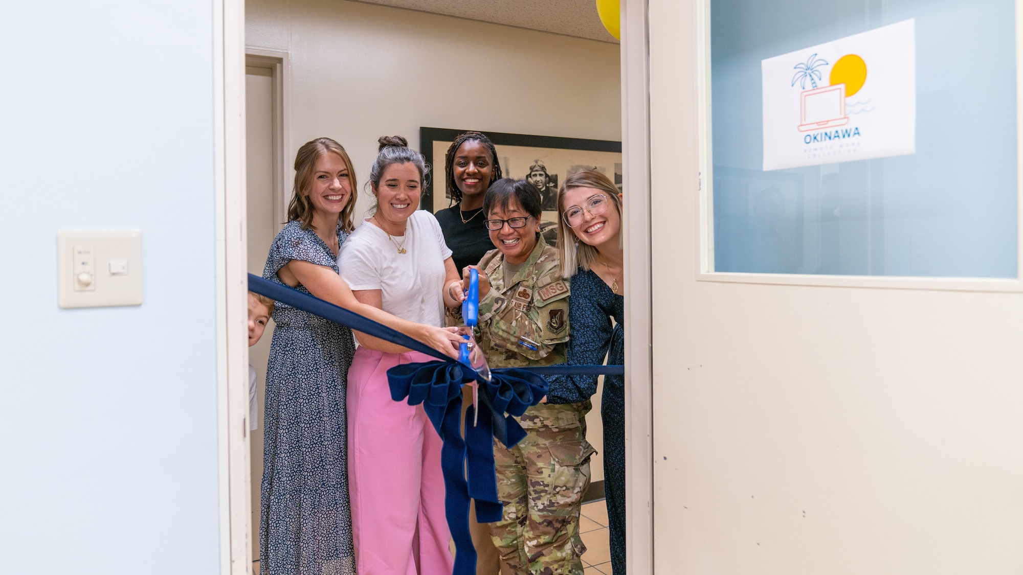 An Airman and spouses cut a ribbon.