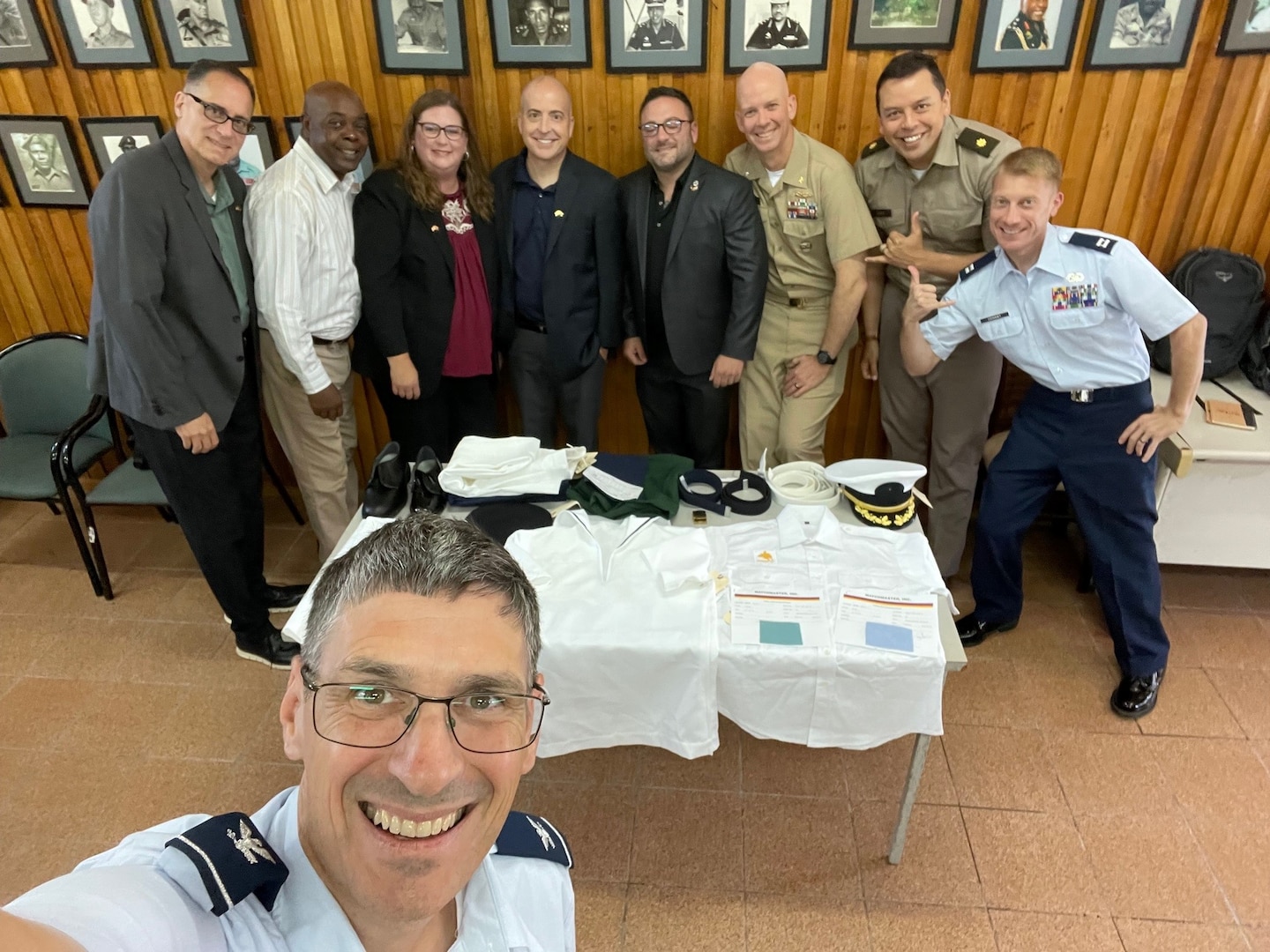 uniformed man takes selfie with other uniformed and civilian men and women