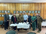 military and civilian men and women pose behind table of uniforms