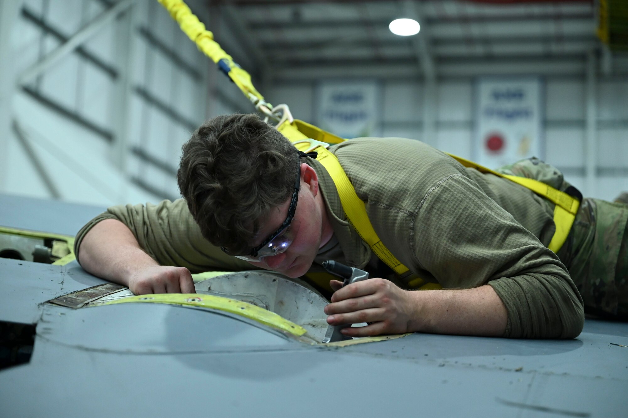Maintainers must wear a safety harness while working on the wing of a jet to prevent injury in the case they fall from the wing.