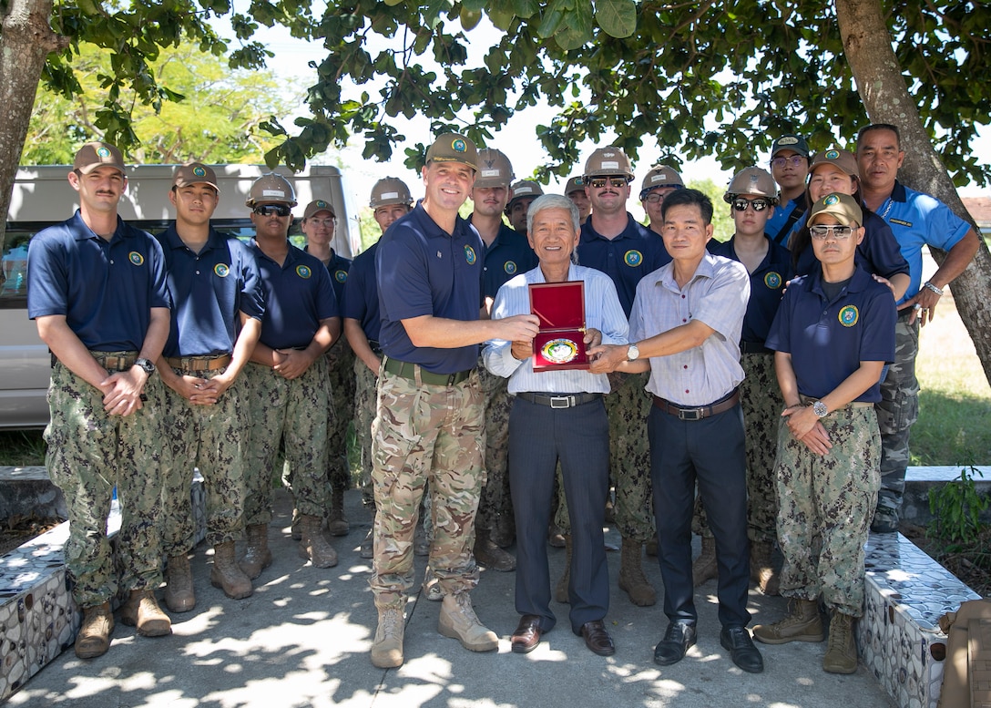 Royal Navy Capt. Joseph Dransfield, Pacific Partnership 2023 Deputy Mission Commander, presents a dedication plaque to Mr. Le Trung Thu, the principal of the Le Quy Don School, a Pacific Partnership 2023 renovation site, at the conclusion of the work completed by the Seabees at the school, Aug. 17