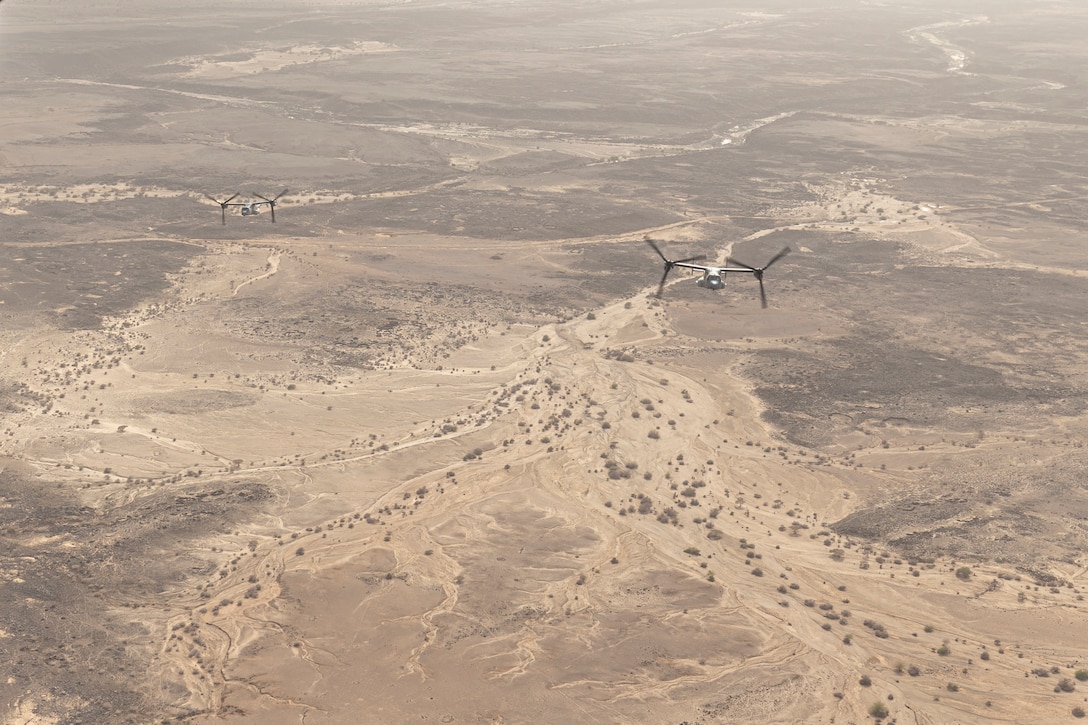 Aircraft fly in formation above a desert.