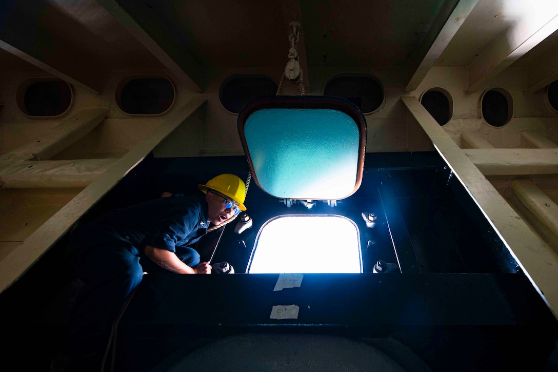 A sailor shouts commands while standing by a window in the forecastle of a ship.