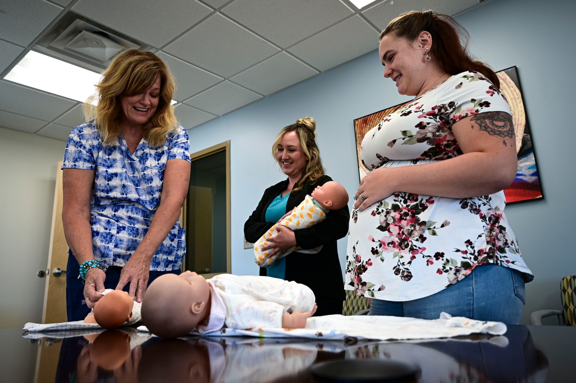 Candi Hutchins, 49th Medical Group parent support nurse, left, and Cassandra Sanchez, 49th MDG family advocacy nurse, center, perform a swaddling class for newborns with Katie Novotney, 49th MDG mental health receptionist at Holloman Air Force Base, New Mexico, Aug. 16, 2023. The Parents 101 class is a part of the New Parent Support Program designed to assist Airmen with newborn and young children and guide them in their path as new parents. (U.S. Air Force photo by Airman 1st Class Isaiah Pedrazzini)