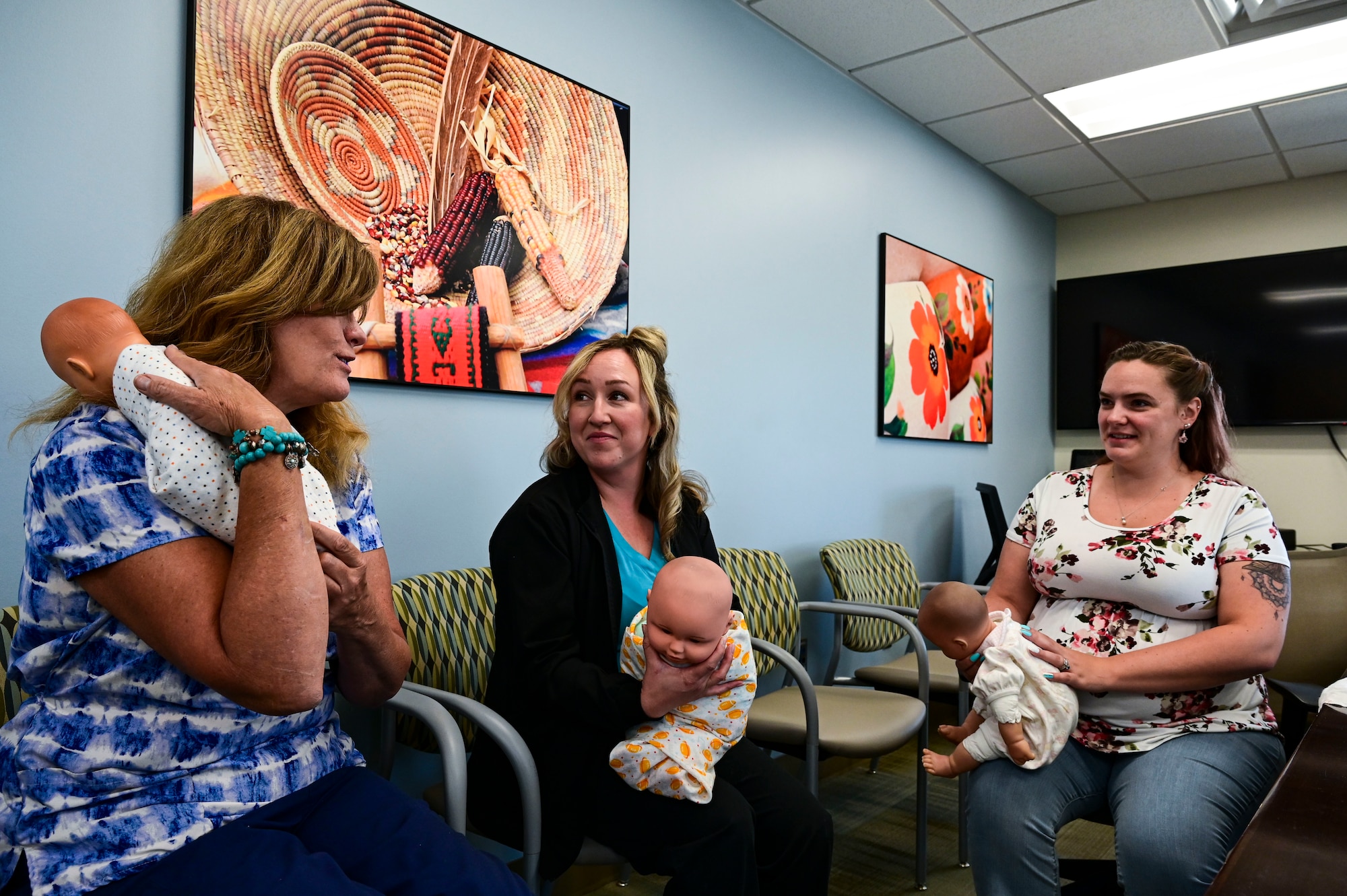 Candi Hutchins, 49th Medical Group parent support nurse, left, and Cassandra Sanchez, 49th MDG family advocacy nurse, center, show Katie Novotney, 49th MDG mental health receptionist how to properly burp a newborn during a Parents 101 class at Holloman Air Force Base, New Mexico, Aug. 16, 2023. The New Parent Support Program is a volunteer system that assists new parents stationed at Holloman in order to help their families learn the basics and skills of parenthood. (U.S. Air Force photo by Airman 1st Class Isaiah Pedrazzini)