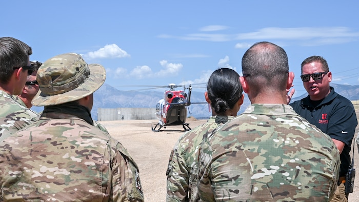 Technicians from the 775th Explosive Ordnance Disposal Flight listen to Cory Cox, AirMed outreach coordinator, as the University of Utah AirMed helicopter lands at 775th EOD's proficiency range Aug. 17, 2023, at Hill Air Force Base, Utah.