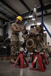 U.S. Army Pfc. Rashad Johnson, a power generator specialist with the 277th Maintenance Company, 110th Combat Sustainment Support Battalion, 78th Troop Command, Georgia Army National Guard, lowers a diesel engine during a training rotation at Camp Dodge, Iowa, Aug. 11, 2023. The rotation enabled Soldiers to train in essential sustainment tasks to ensure mission readiness.