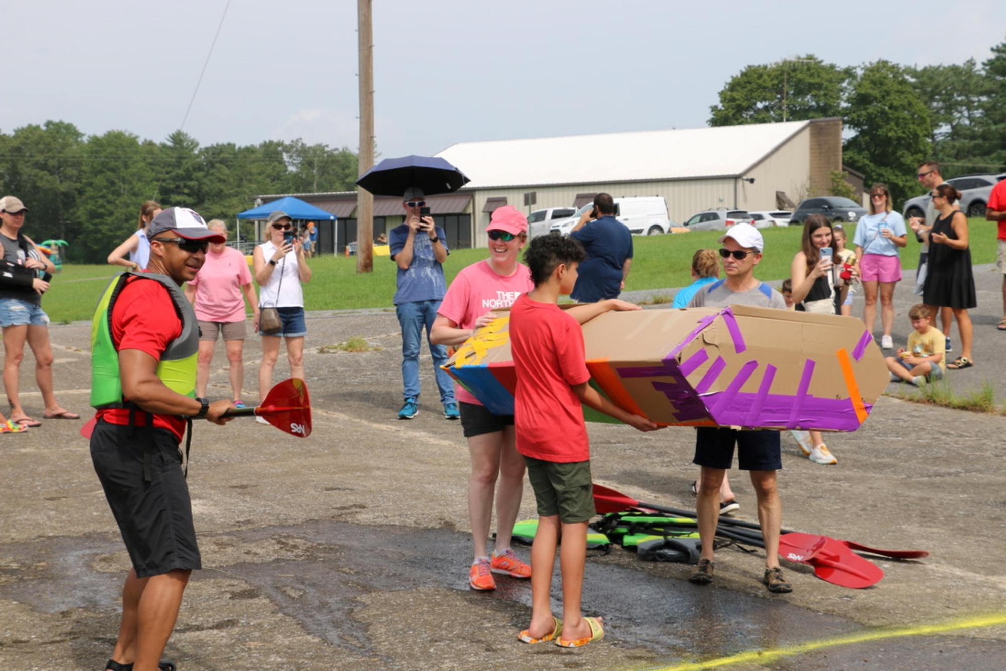 Arnold Engineering Development Complex Commander Col. Randel Gordon, left, offers some encouragement as the teams participating in the cardboard boat race prepare to take their creations to the water during the first-ever Arnold Air Force Base Services SummerFest Aug. 12, 2023, at the Gossick Leadership Center on Arnold Air Force Base, Tenn. Along with the cardboard boat race, the event featured pie eating contests, a car show, a dunking booth, bounce houses and food trucks, among other activities. (U.S. Air Force photo by Jodee George)