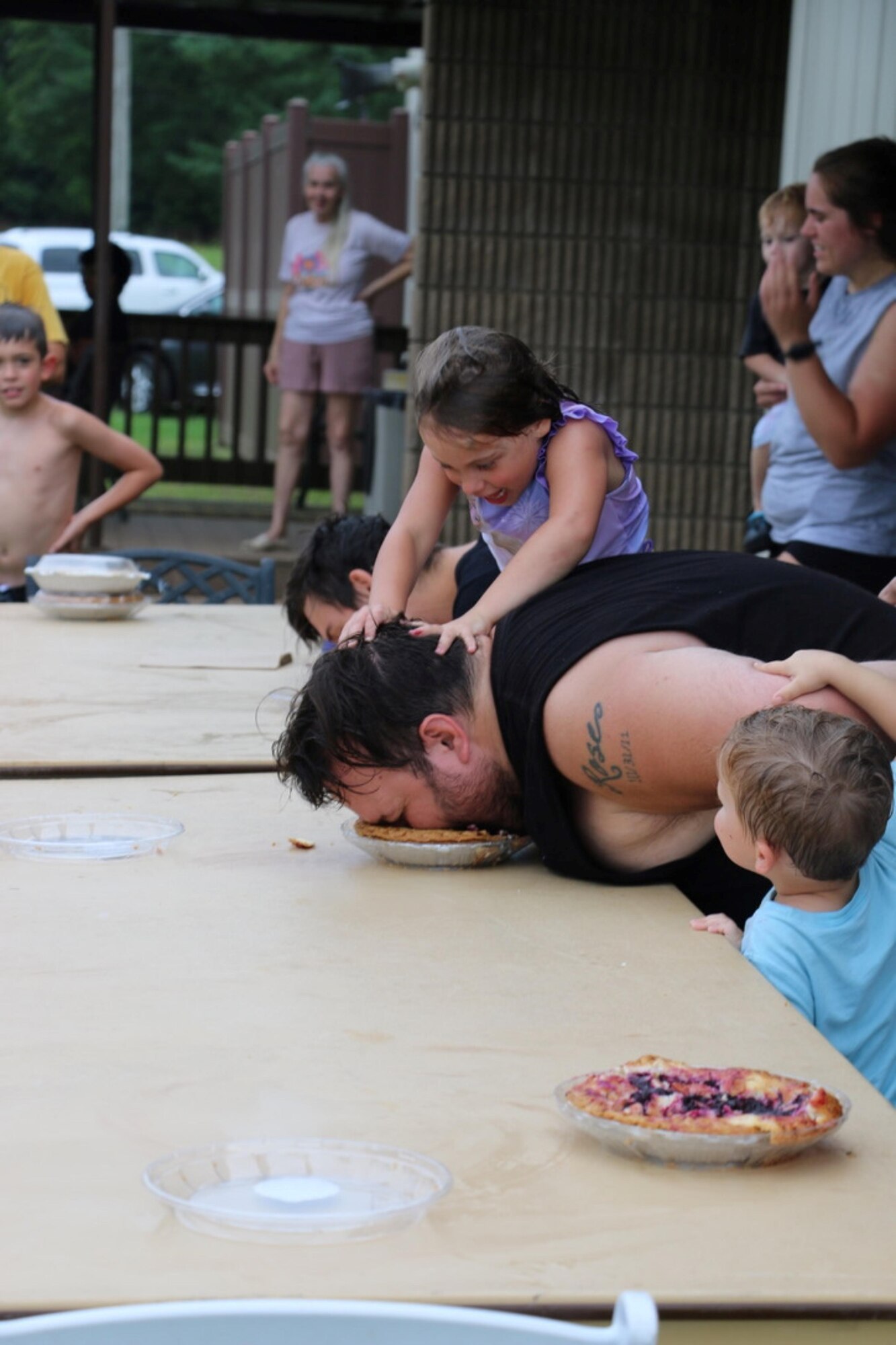 A contestant receives a little extra encouragement during the adult pie eating contest held as part of the first-ever Arnold Air Force Base Services SummerFest Aug. 12, 2023, at the Gossick Leadership Center on Arnold Air Force Base, Tenn. Along with both a children’s pie eating contest and adult pie eating contest, the event featured a car show, a cardboard boat race, a dunking booth, bounce houses and food trucks, among other activities. (U.S. Air Force photo by Jodee George)