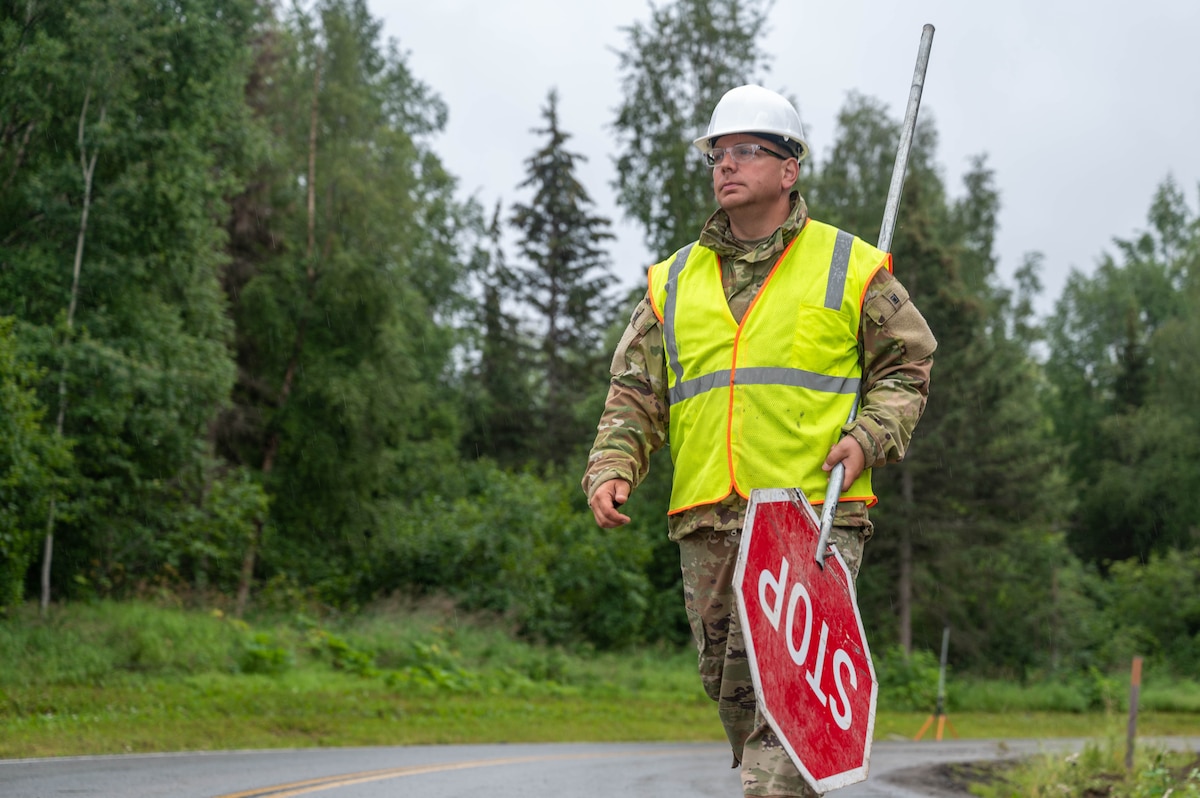 Staff Sgt. Ben Miller, a 934th Airlift Wing Civil Engineering Squadron pavement equipment operator, walks with a stop sign during the upgrade of Camp Mad Bull’s electrical system at Joint Base Elmendorf-Richardson, Alaska, on Aug. 9, 2023. The 934 AW CES was at the site for over two months in a series of 3 different rotations to effectively complete the mission. (Air Force photo by Senior Airman Matthew Reisdorf)