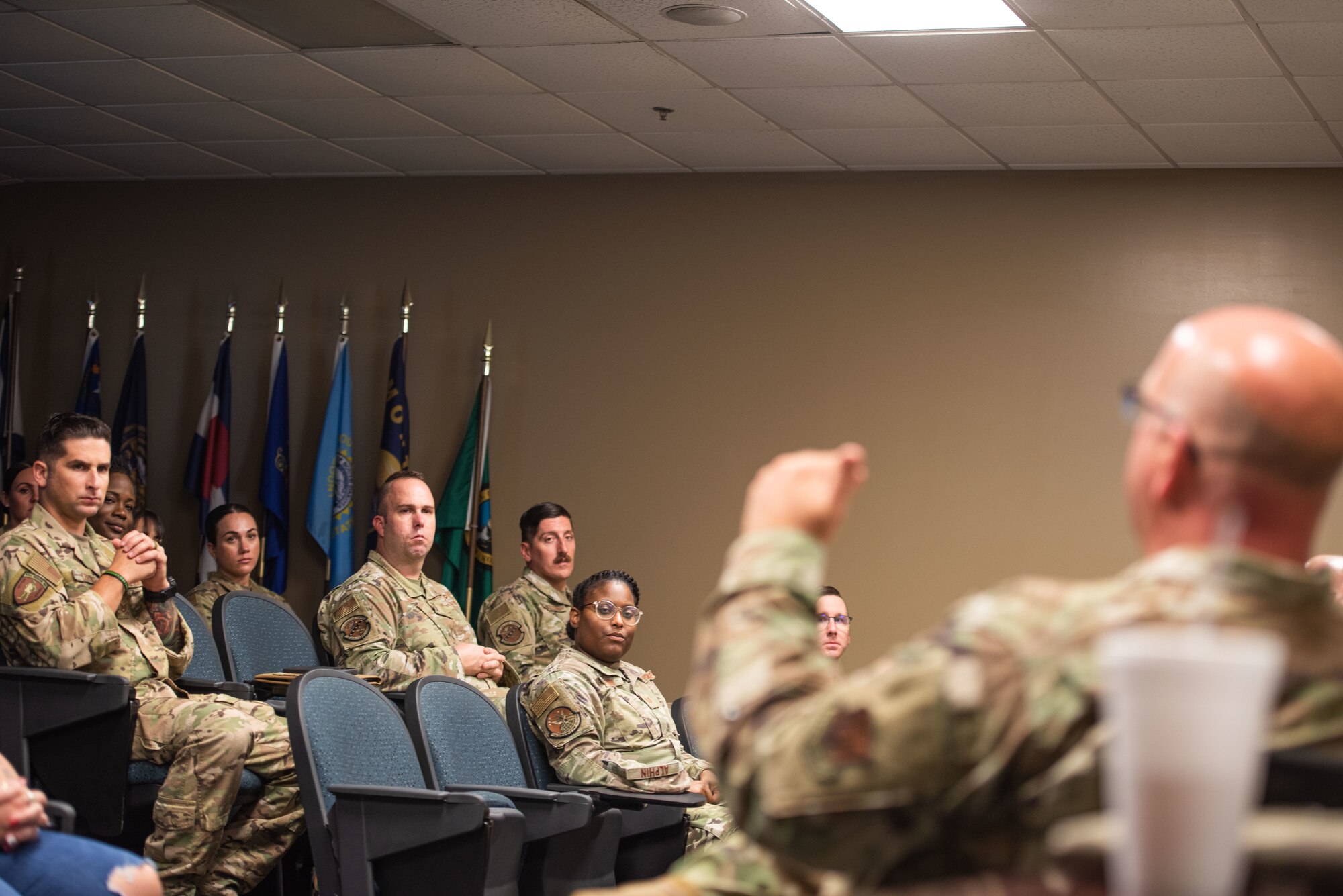 Multiple Airmen intensively listen to a chief speak during a chiefs panel,