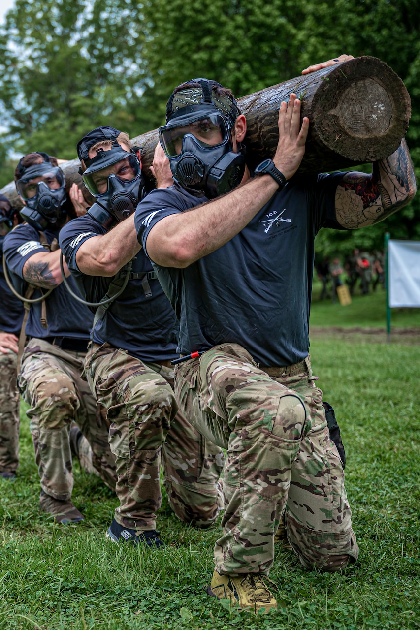 National Guardsmen lunge in formation while carrying a log.