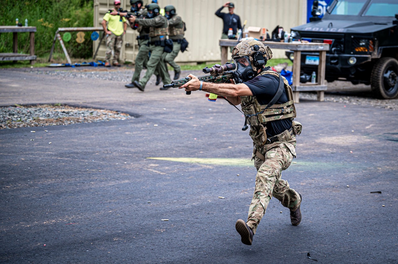 A soldier carrying a weapon moves on pavement.