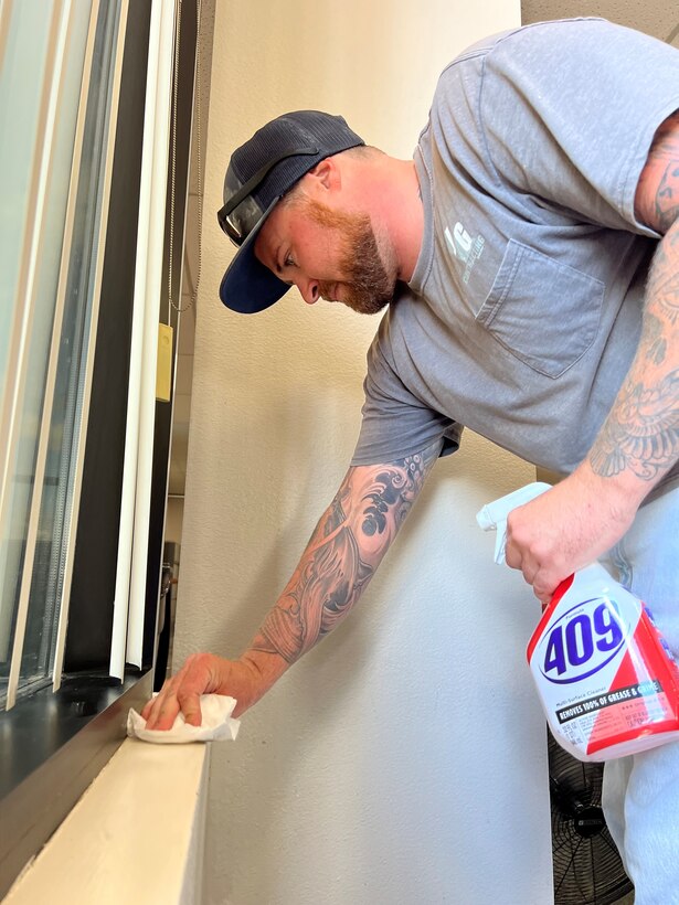 Cody Brown, a 412th Civil Engineer Group contractor, removes water residue from a sill in wing headquarters Monday.