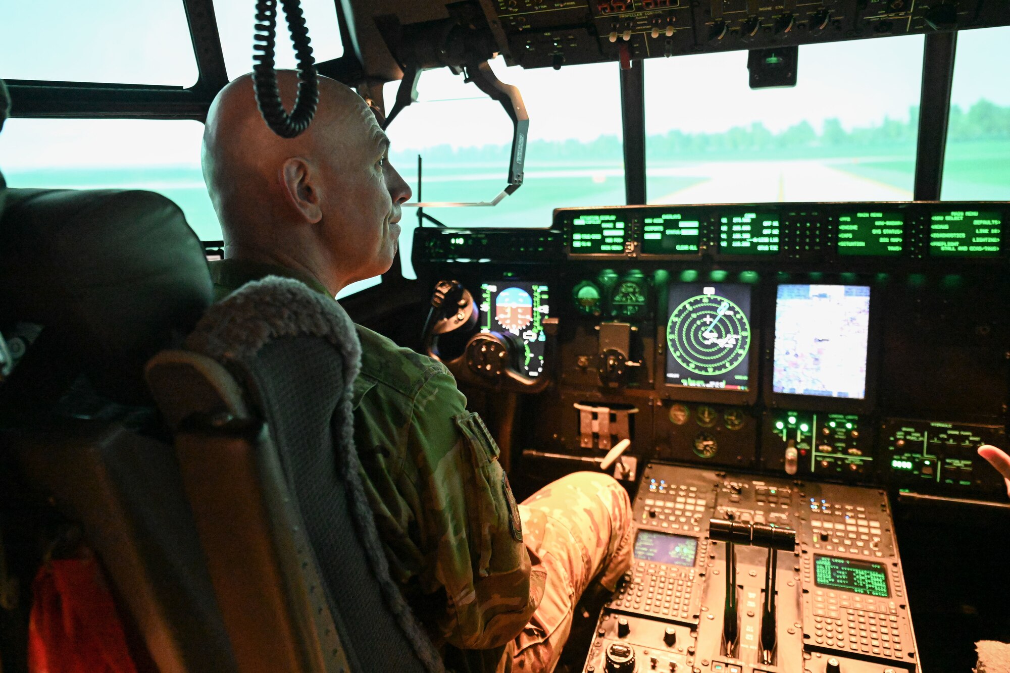 man in uniform sits in the cockpit of a C-130J
