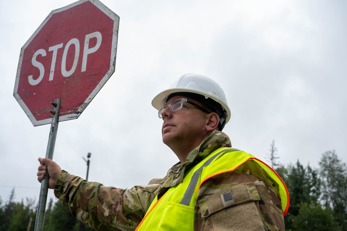 Staff Sgt. Ben Miller, a 934th Airlift Wing Civil Engineering Squadron pavement equipment operator, holds a stop sign during the upgrade of Camp Mad bull’s electrical system at Joint Base Elmendorf-Richardson, Alaska, on Aug. 9, 2023. The 934 AW CES was at the site for over two months in a series of 3 different rotations to effectively complete the mission. (Air Force photo by Senior Airman Matthew Reisdorf)
