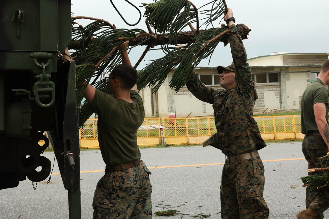U.S. Marine Corps Cpl. Matthew Kamm, left, a transmission systems operator, and Lance Cpl. Ali Fish, right, a data system administrator, both with Communications Company, Headquarters Battalion, 3rd Marine Division, load a fallen tree into a USMC 7-ton on Camp Courtney, Okinawa, Aug. 7, 2023. Typhoon Khanun moved through Okinawa as a category 4 hurricane equivalent storm, bringing strong winds, heavy rain, and high waves, marking one of the strongest storms to affect the island in recent years. Immediately after the storm, crews from across Marine Corps Installation Pacific and III Marine Expeditionary Force began assessing damage and initiating repair work to ensure the Marines on Okinawa remain operationally ready. Kamm is a native of Concord, California, and Fish is a native of Adel, Georgia.