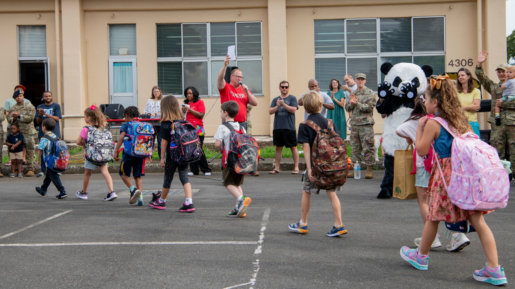 Students walk in a line past parents and community members.
