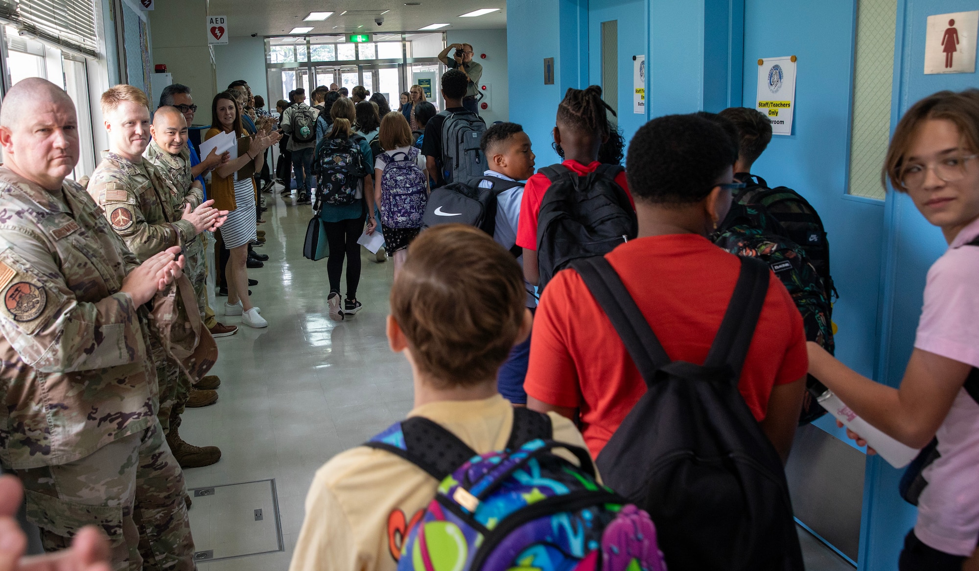 Students walk down a hallway lined with community members.