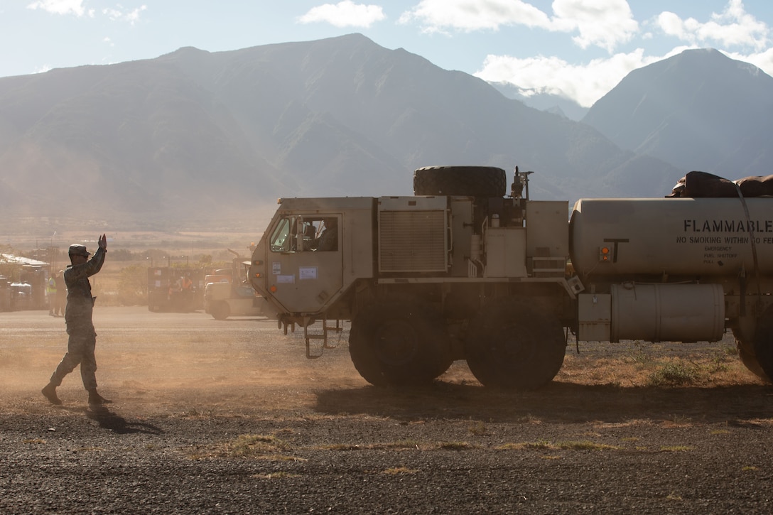 A service member gives directions to a military vehicle.