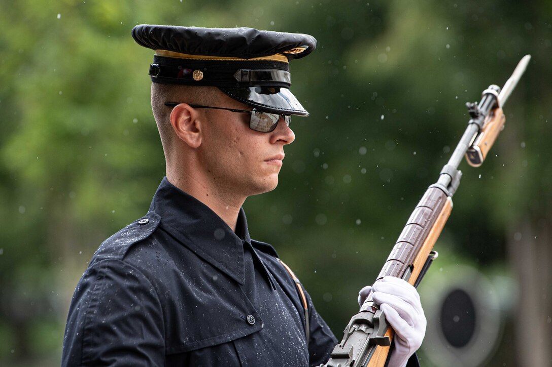 A soldier stands at attention in the rain.