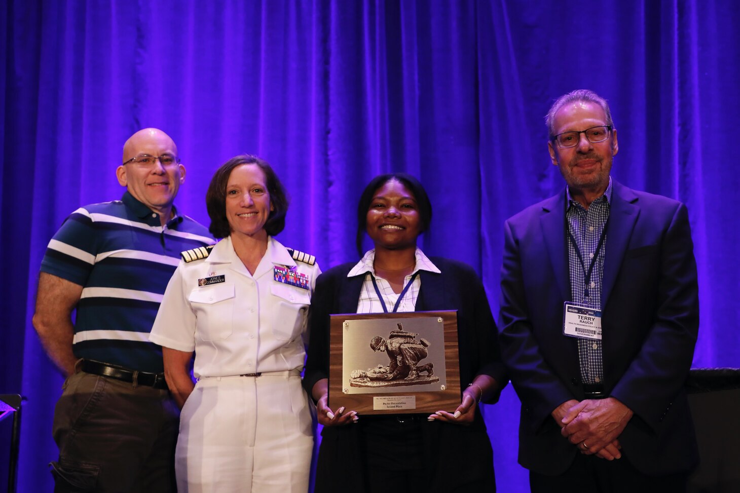 KISSIMMEE, Fla. (Aug. 17, 2023) Leadership and staff with Naval Medical Research Command (NMRC) and NMRC's Biological Defense Research Directorate (BDRD), pose with a second-place award for the poster sessions at the Military Health System Research Symposium (MHSRS). BDRD received the award for research into high-efficacy assays for the detection of SARS-CoV-2 (the virus that causes COVID-19). MHSRS is the Department of Defense's premier scientific meeting that focuses specifically on the unique medical needs of the Warfighter. This annual educational symposium brings together healthcare professionals, researchers, and DoD leaders for four days of critical learning, intensive idea sharing, and relationship building. The Naval Medical Research & Development enterprise, comprised of eight commands and led by NMRC, is engaged in a broad spectrum of activity from basic science in the laboratory to field studies in austere and remote areas of the world to investigations in operational environments. In support of the Navy, Marine Corps, and joint U.S. warfighters, researchers study infectious diseases, biological warfare detection and defense, combat casualty care, environmental health concerns, aerospace and undersea medicine, medical modeling, simulation, operational mission support, epidemiology, and behavioral sciences. (U.S. Navy Photo by Sidney Hinds/released)